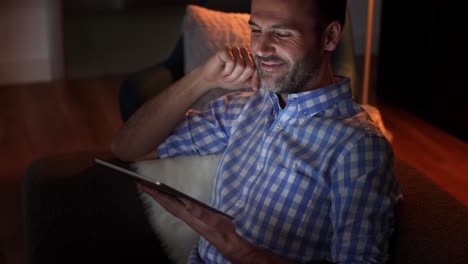 hombre sonriente usando una tableta por la noche