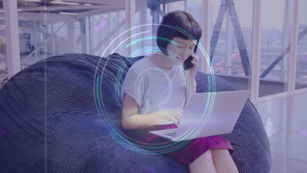animación de escáner redondo de neón contra mujer asiática hablando en teléfono inteligente y usando computadora portátil en la oficina