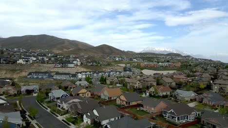 Single-family-homes-in-the-foothills-of-Travers-Mountain-in-Lehi,-Utah-with-snow-capped-peaks-in-the-distance---aerial-flyover