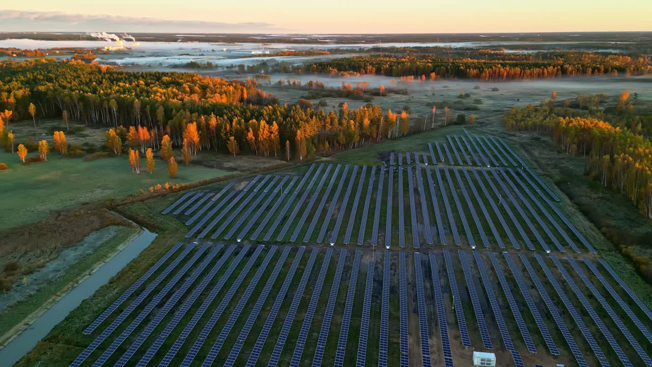 Luftfoto: Solcellepark ved solnedgang og en skov, vedvarende energi, parallax droneoptagelse