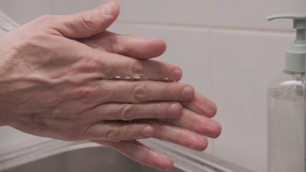 Kvinde vasker hænder med flydende sæbe på badeværelset