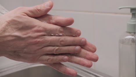 man washing her hands with liquid soap in the bathroom