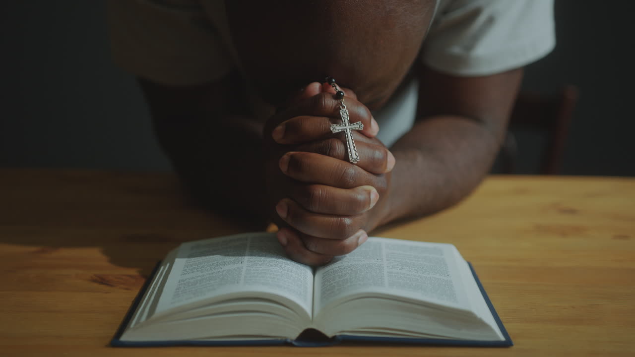 Black Man Holding Crucifix on Bible and Praying in Times of Despair
