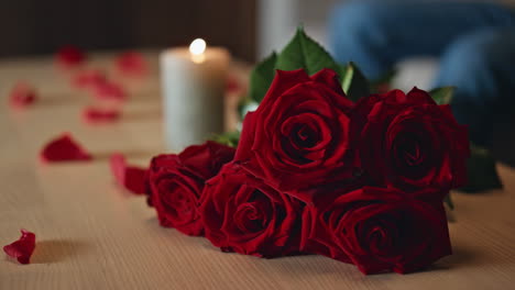 beautiful roses bouquet lying on table near burning candle close up. red flowers