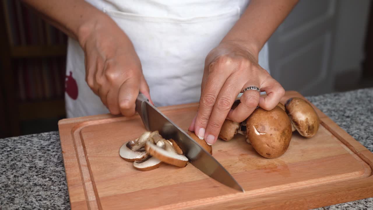 Woman's Hands Slicing Fresh Mushrooms On A Chopping Board