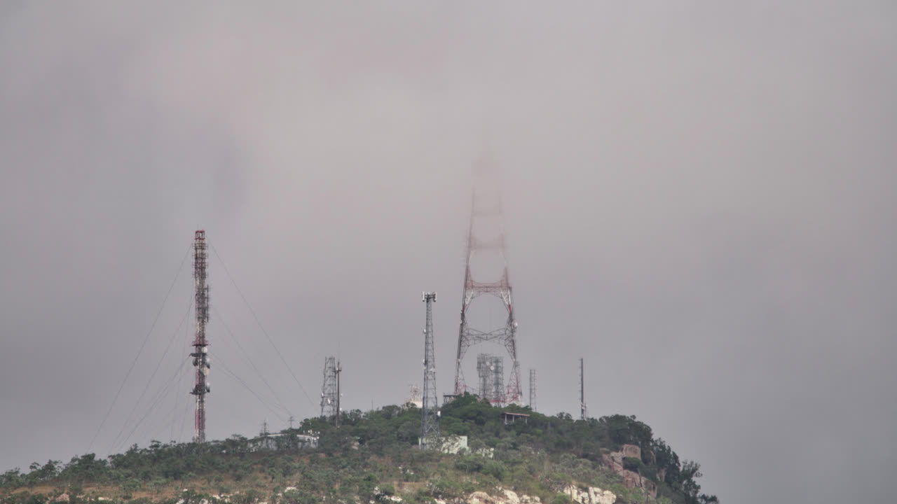 통신 타워가 천천히 구름을 통해 드러나는 폭풍우의 회색 날 산 꼭대기, 스티워트 산, 타운스빌, 오스트레일리아