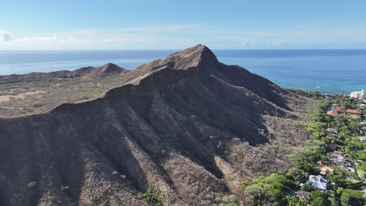 Aerial drone footage along the rim of Diamond Head volcanic crater on Oahu, Hawaii, showcasing panoramic tropical landscapes, turquoise ocean views, palm trees, and the scenic Waikiki coastline below