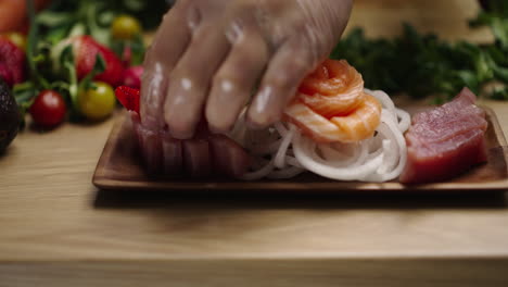 chef plating fresh sashimi with tuna, salmon, and strawberries