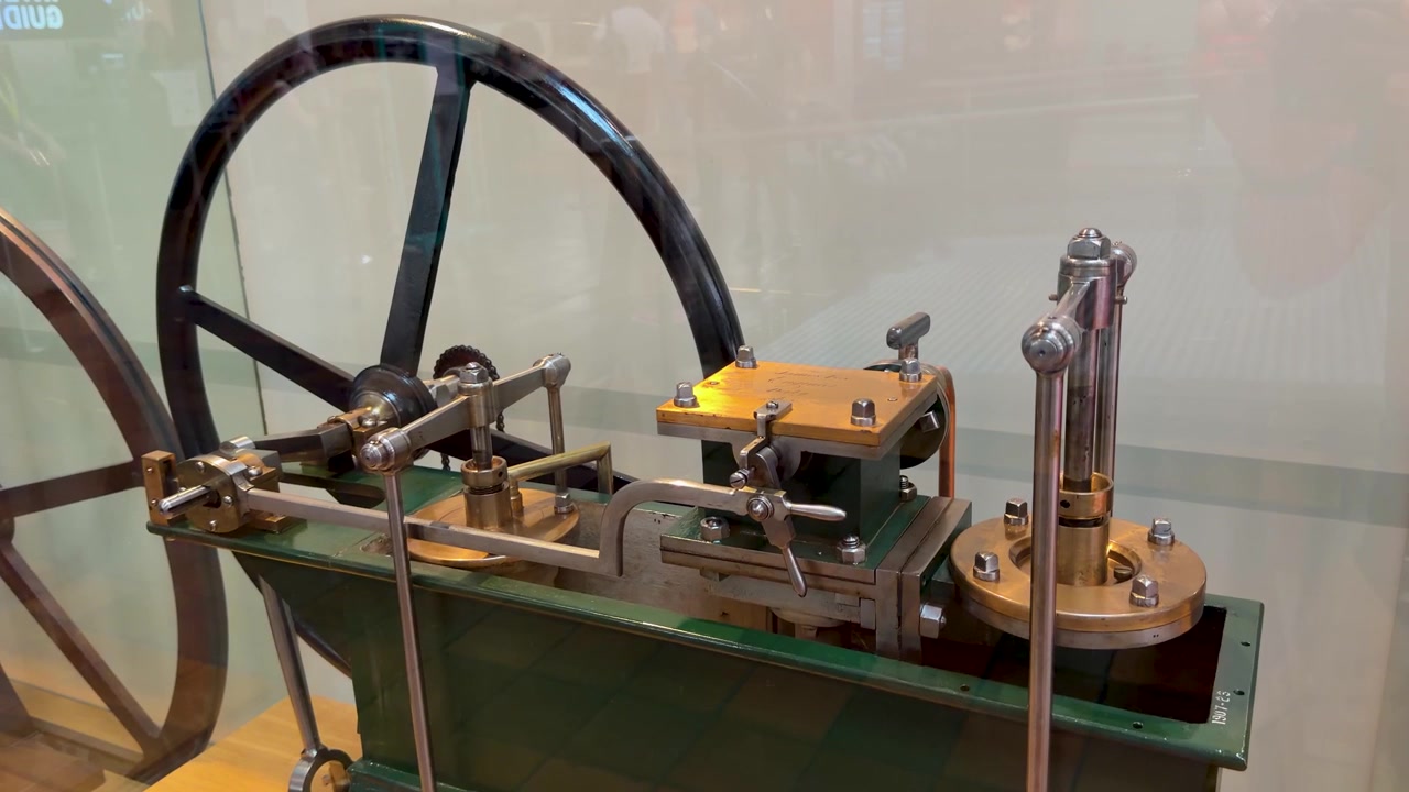 Detailed shot of a vintage brass and steel steam engine mechanism in motion indoors.