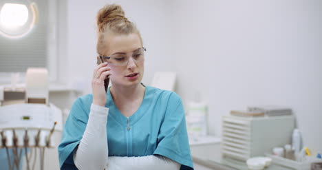 Female-Doctor-Talking-On-Mobile-Phone-At-Healthcare-Clinic-3