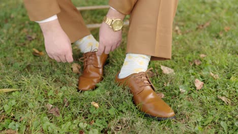 groom ties his shoes while getting ready for his wedding