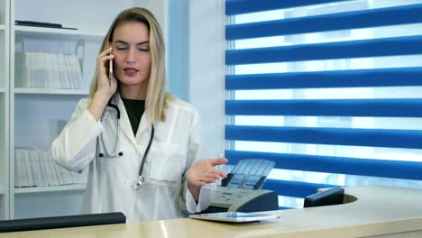 stressed female medical worker yelling while speaking on phone at hospital reception