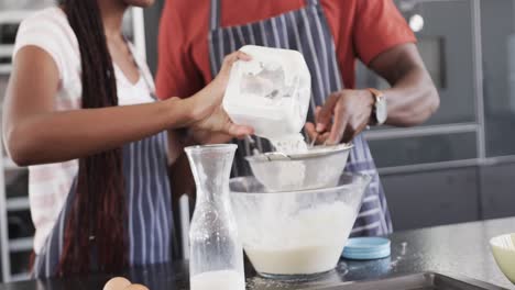 feliz pareja afroamericana en delantales horneando juntos en la cocina, cámara lenta