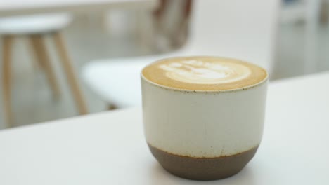 una taza de café tarde con diseño en forma de flor en la parte superior en la cafetería