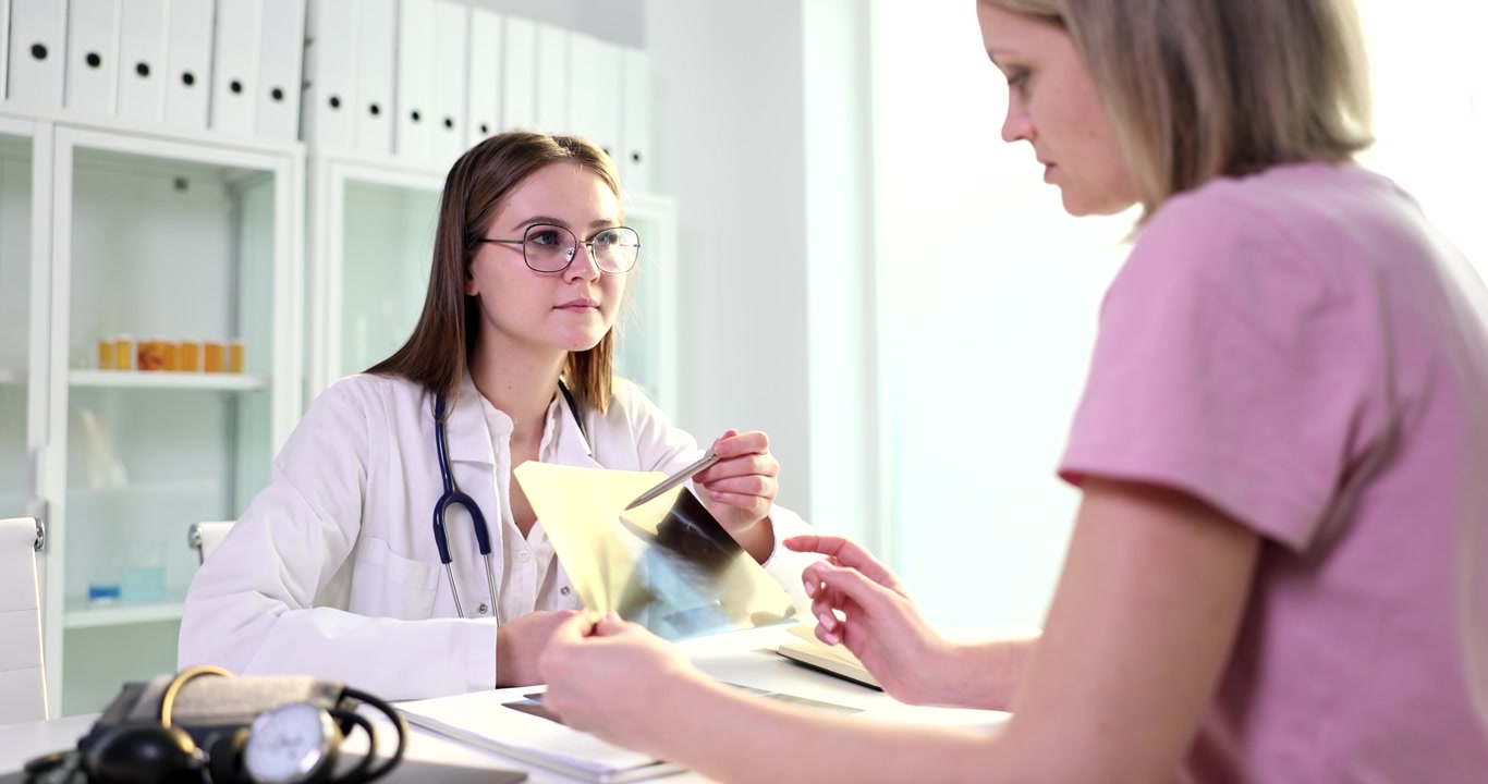 Læge diskuterer røntgenresultater med patient i et moderne klinikmiljø.