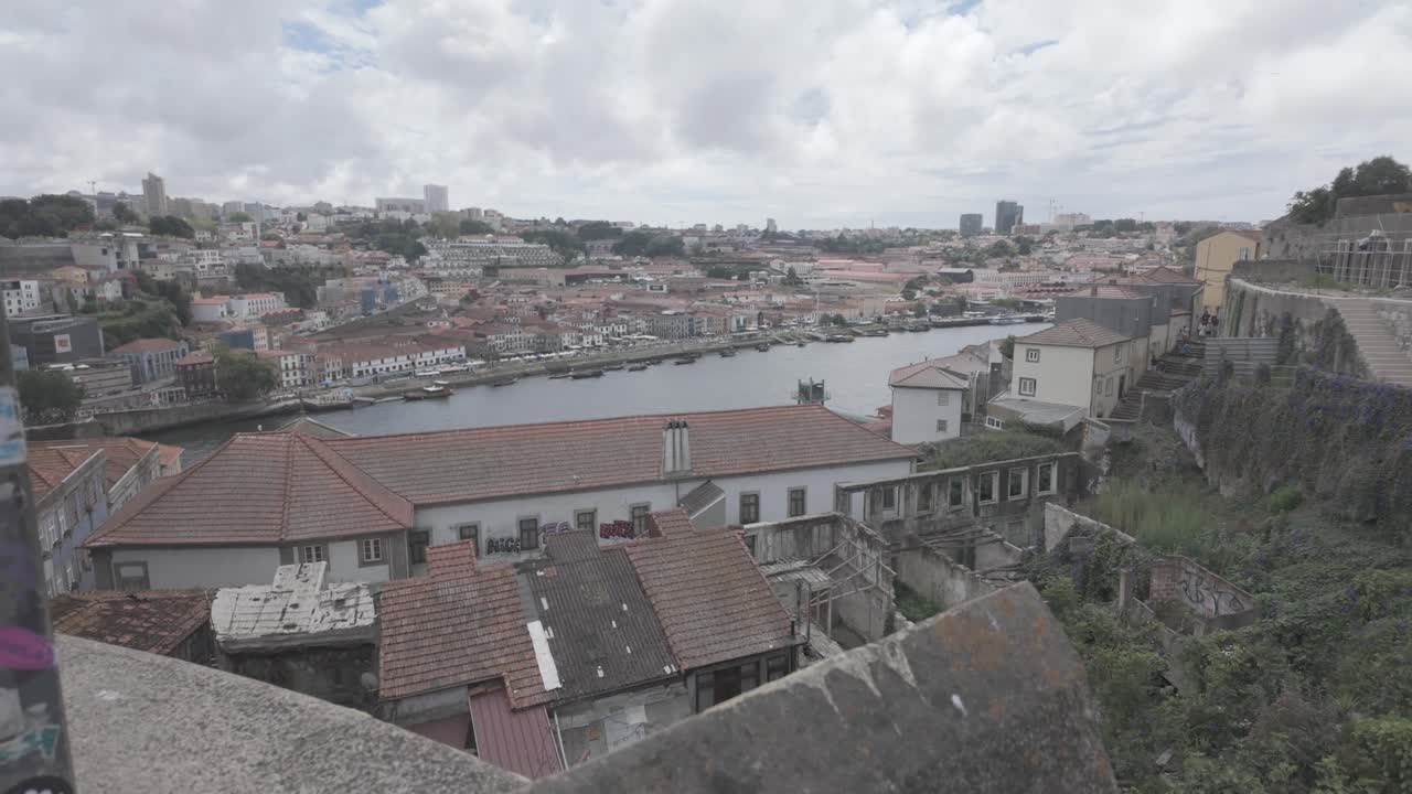 People walking on a sunny day along a graffiti-lined street near Porto's Luís I Bridge