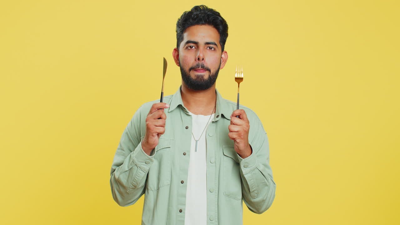 ⁇ 주린 남자가 저녁 식사를 위해 기다리고 있습니다. 불안함으로 식사 접시를 들고 식기 포크 칼을 들고 있습니다.