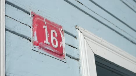 house number 16 on light blue wooden wall