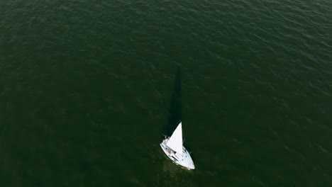 top down aerial view of sailboat sailing on water reservoir, zagrze lake, poland, high angle drone shot