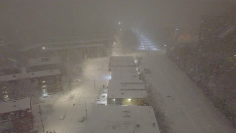 blizzard sweeps over city streets of montréal at night, with streetlights glowing dimly, high-angle view