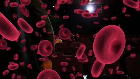 Animation-of-red-blood-cells-over-people-in-cinema