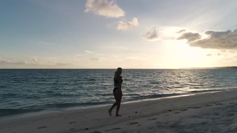 silhouette of woman running and walking on exotic white island beach at sunrise