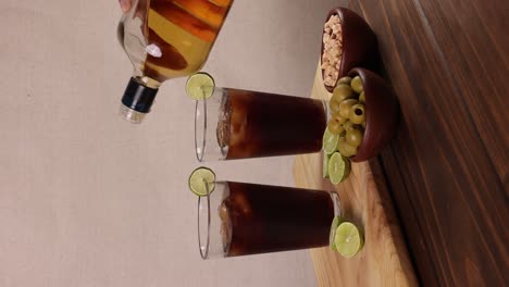 chilean piscola drink typical summer cocktail of chile glass with ice wooden board and lemons in bright background with selective focus