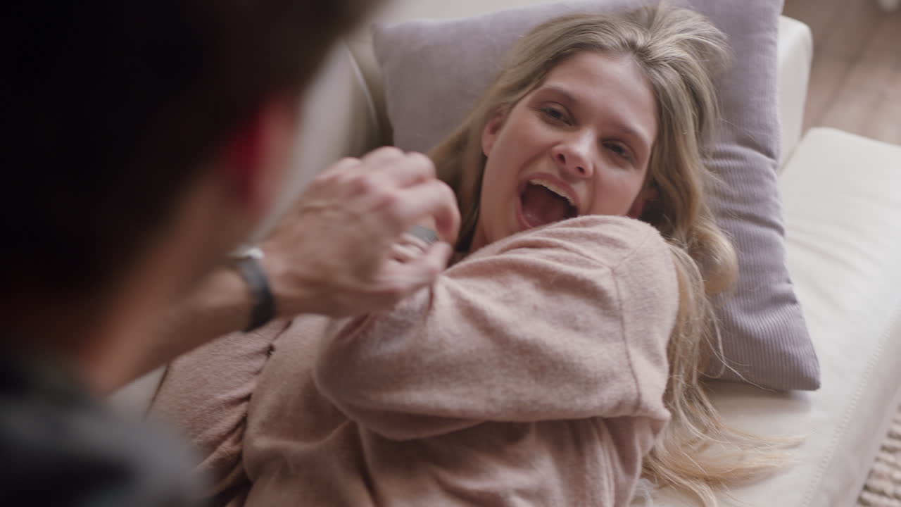 счастливая молодая пара фотографируется вместе с помощью камеры, развлекается дома на диване, весело наслаждается романтическими отношениями, фотографирует друг друга, делает лица.