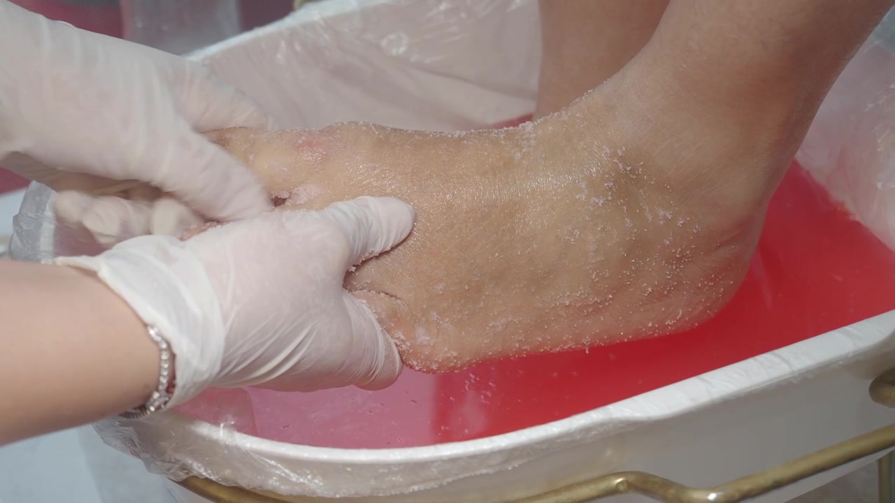 Estetista che applica uno scrub per i piedi durante un trattamento di pedicure.