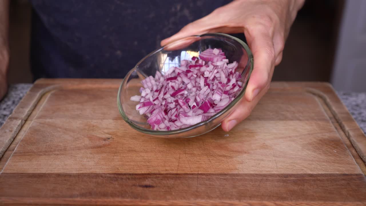 Cook showing purple onion cut in dices
