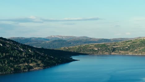 Tranquilo-Lago-Azul-Con-Montañas-Boscosas-En-El-Fondo