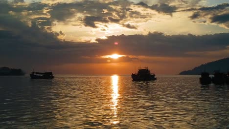 Toma-En-Cámara-Lenta-De-La-Puesta-De-Sol-Sobre-Los-Barcos-En-Una-Bahía-En-Borneo,-Malasia