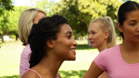 smiling women in pink for breast cancer awareness in the park chatting