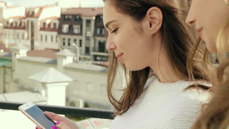 two young women using a smartphone on a rooftop