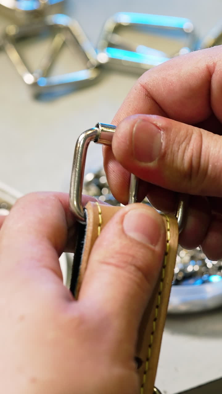 Fashion master is working on exclusive leather accessories. Tailor sews a belt with a special equipment in workshop. Vertical video