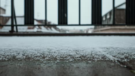 Close-up-time-lapse-footage-of-heavy-wet-snow-flakes-falling-onto-a-concrete-balcony