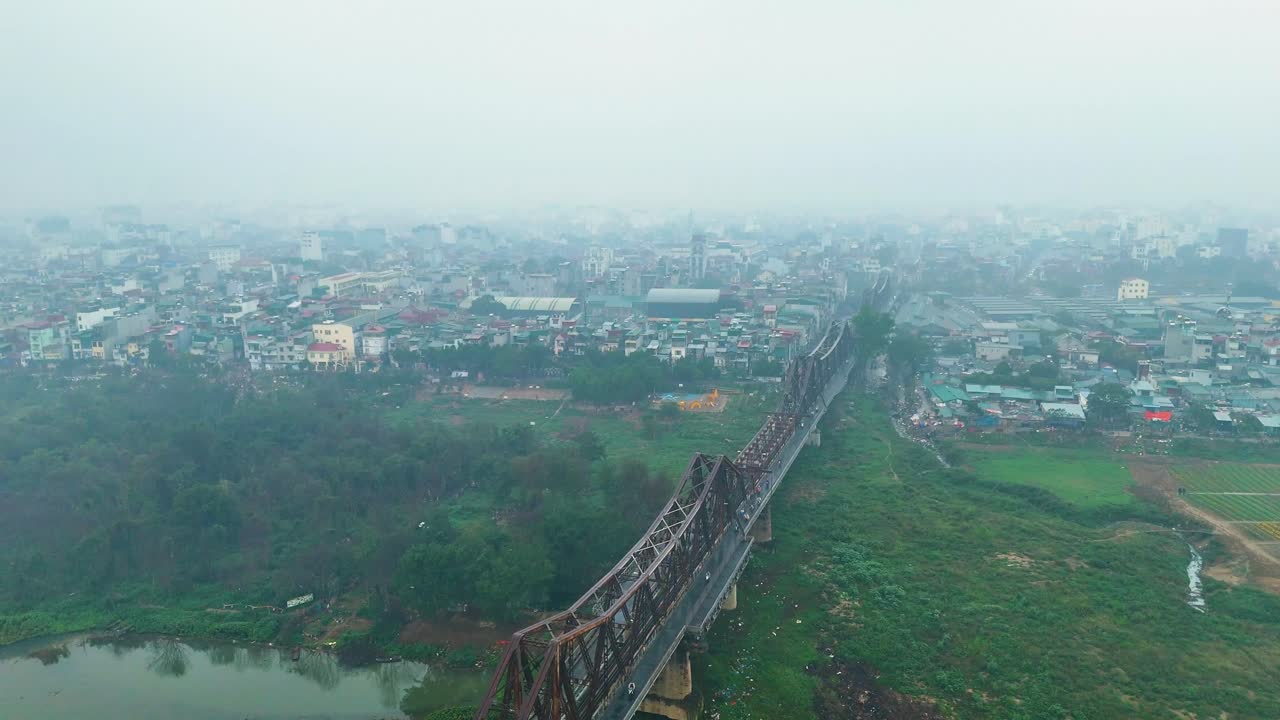 Drone shot of Hanoi's Long Bien Bridge in Vietnam, with a hazy atmosphere caused by extreme pollution.