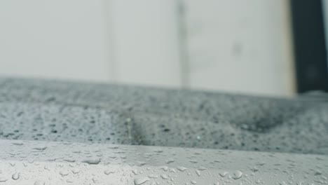 gotas de lluvia en el parabrisas de la ventanilla trasera de un coche gris