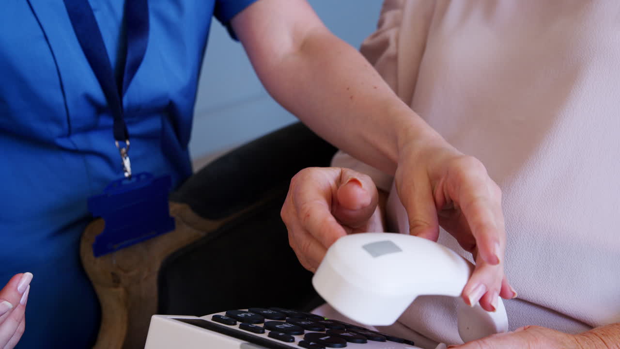 enfermera de la comunidad mostrando a una mujer mayor cómo usar un teléfono de gran tamaño
