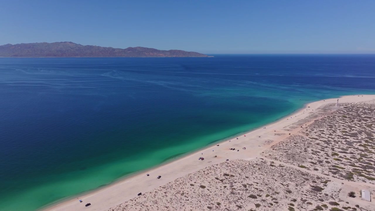 Penerbangan drone 4K yang mulus di atas pantai berpasir murni Punta Arena, La Ventana, menangkap warna laut yang cerah dan pemandangan ikonik Isla Cerralvo