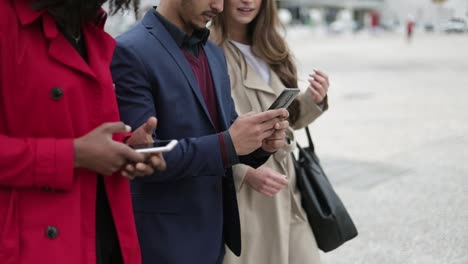 Caucasian-and-Afro-american-women-talking,-man-texting-on-phone