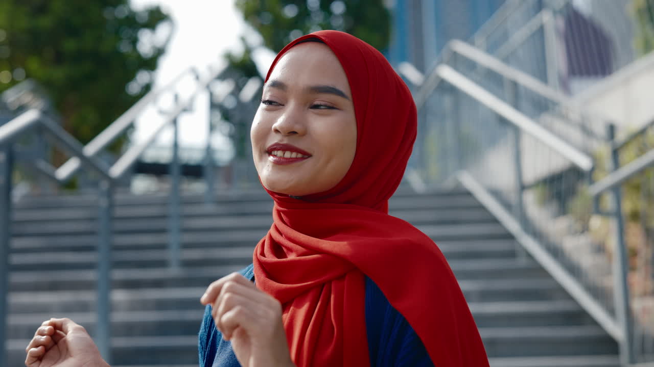 Portrait of a Smiling Young Woman in a Red Hijab Outdoors