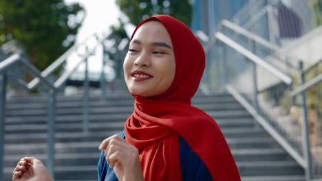 portrait of a smiling young woman in a red hijab outdoors