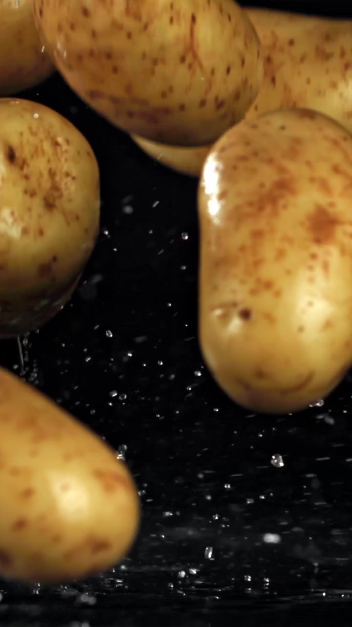 Movimento rallentato di patate fresche che cadono con schizzi d'acqua.