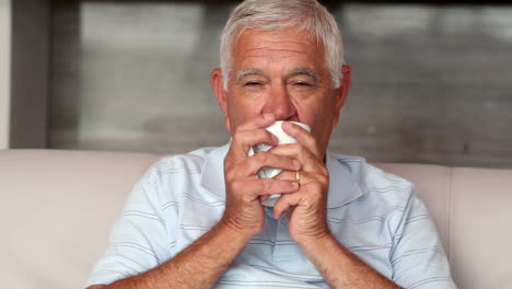 senior man drinking cofffee on couch