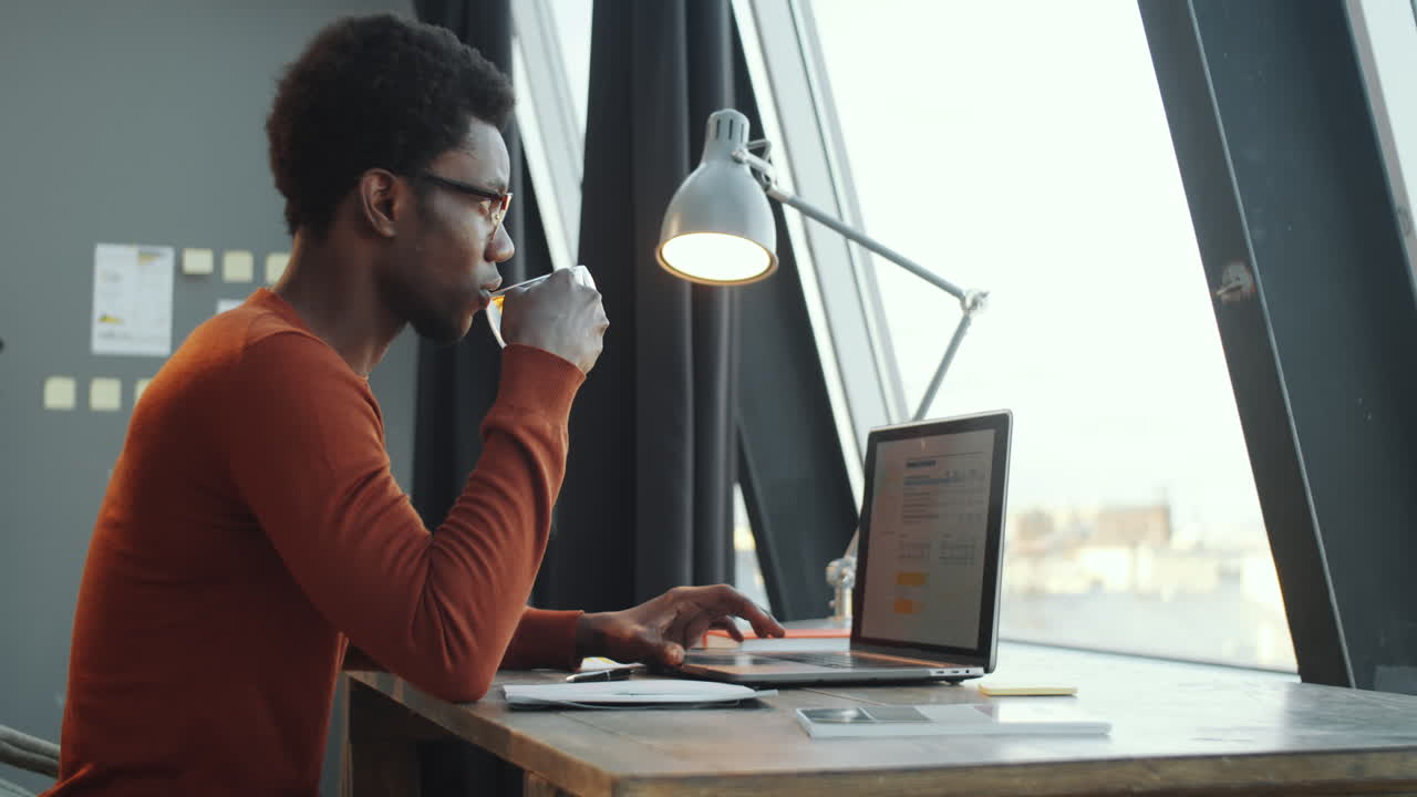 African American Businessman Using Laptop and Drinking Tea in Office