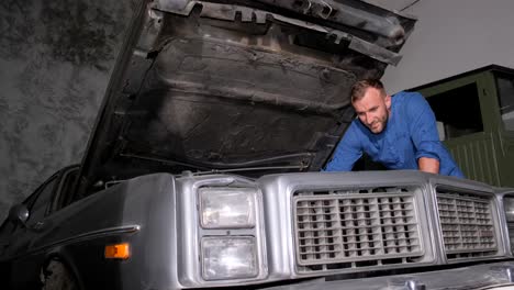 man repairing an old car in a garage