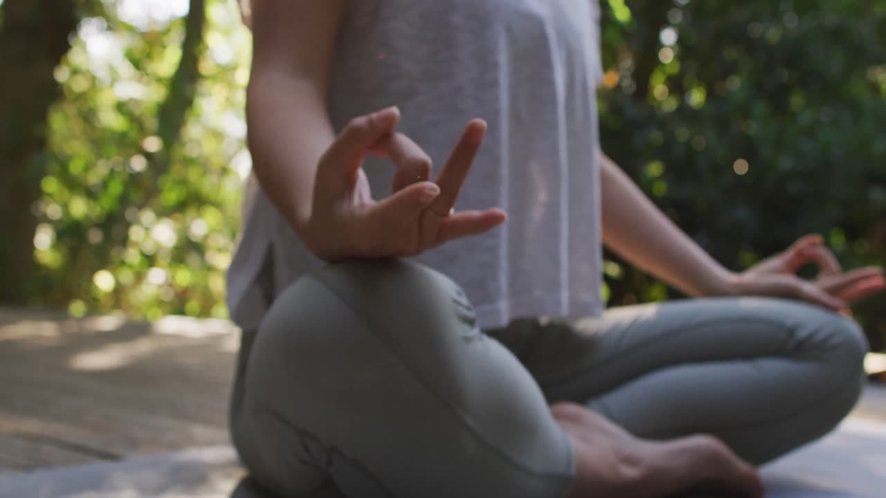 mujer asiática meditando y sentada en un tapete de yoga en el jardín