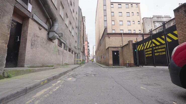 Woman in yellow jacket walking down an alleyway with people in distance