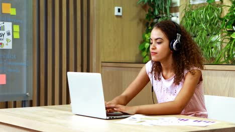 ejecutiva escuchando música mientras usa una computadora portátil